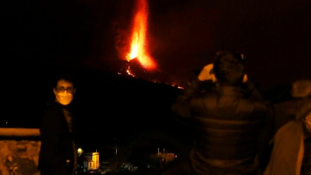 Varias personas observan la actividad nocturna del volcán de La Palma este domingo, cuando se cumplen tres semanas de la erupción. EFE/ Elvira Urquijo A.