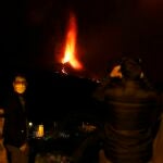Varias personas observan la actividad nocturna del volcán de La Palma este domingo, cuando se cumplen tres semanas de la erupción. EFE/ Elvira Urquijo A.