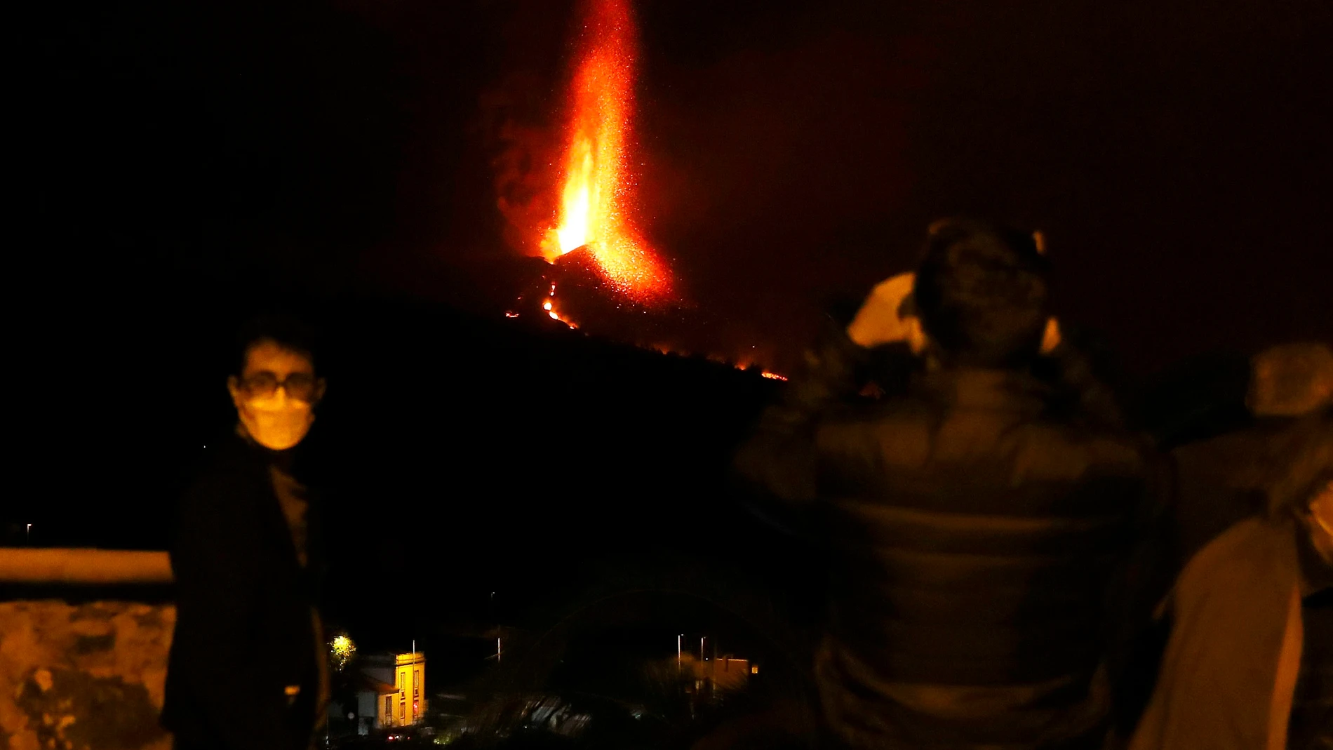 Varias personas observan la actividad nocturna del volcán de La Palma este domingo, cuando se cumplen tres semanas de la erupción. EFE/ Elvira Urquijo A.