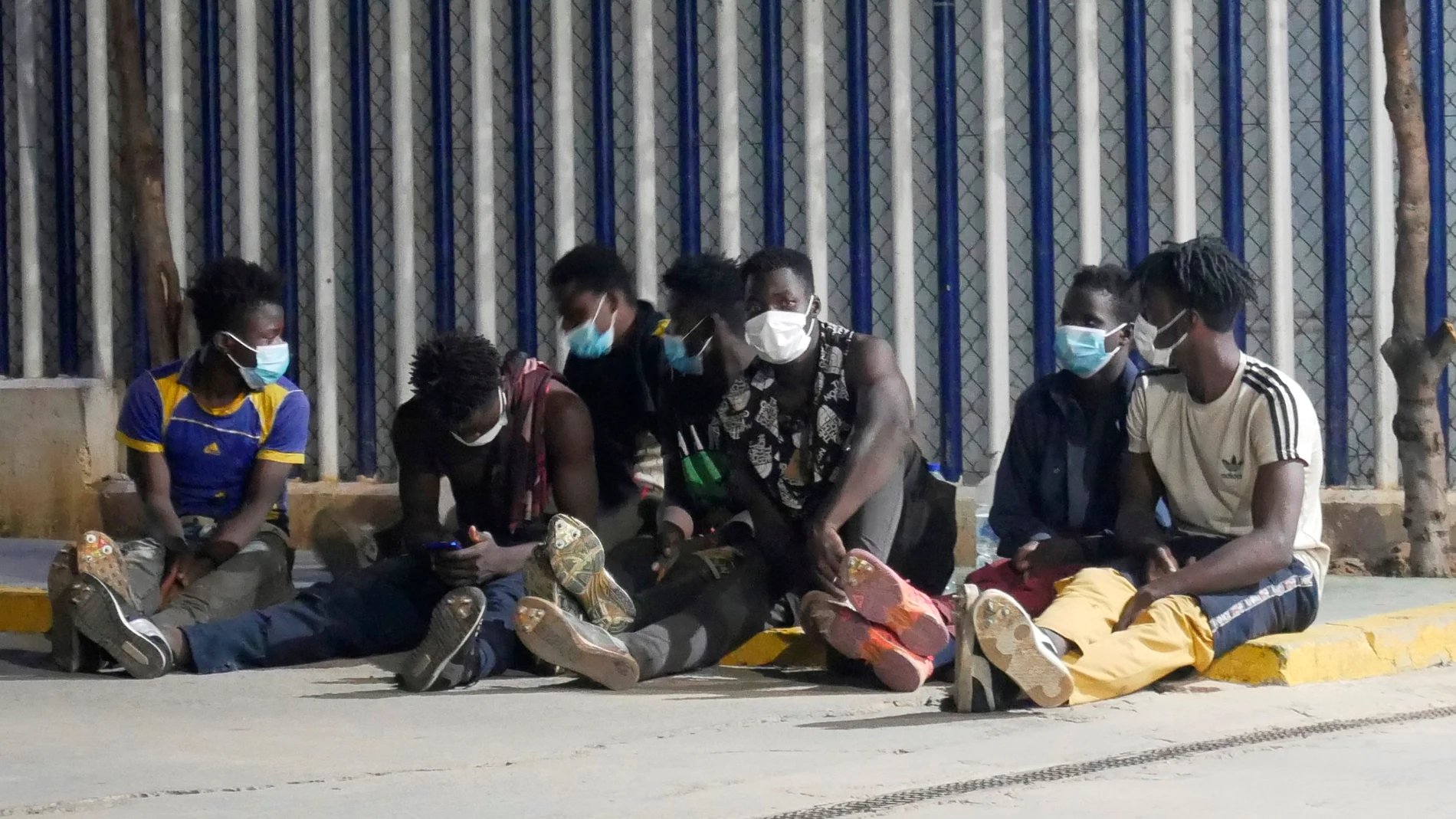 Varios migrantes de origen subsahariano permanecen bajo vigilancia policial tras acceder a Melilla saltando el perímetro fronterizo entre España y Marruecos EFE/Paqui Sánchez