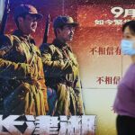 Una mujer china junto a un cartel de la película "La Batalla del Lago Changjin"