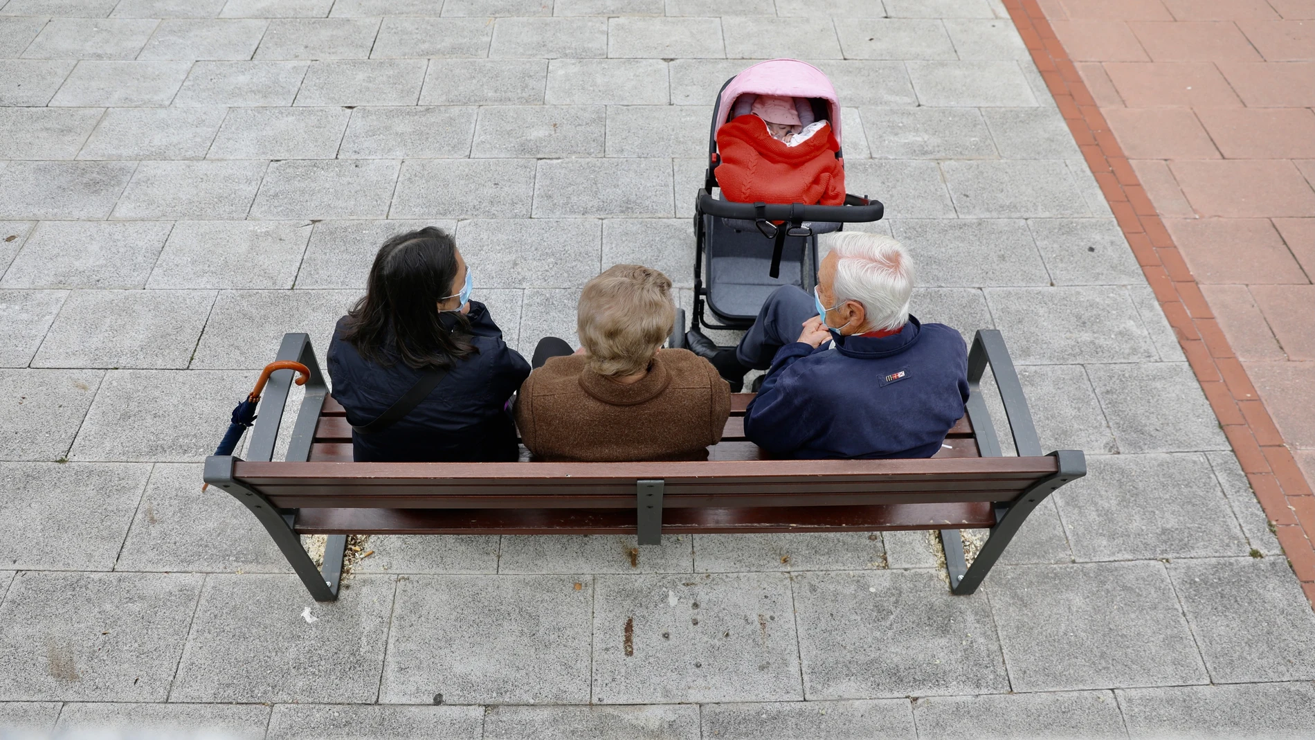 Varios pensionistas charlan sentados en un banco