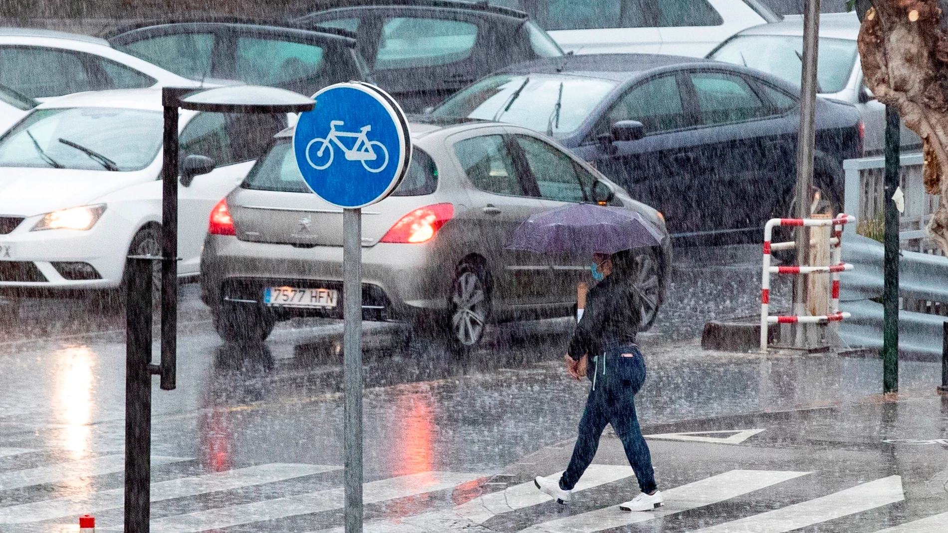 Una mujer cruza un paso de peatones bajo una intensa tormenta en Murcia