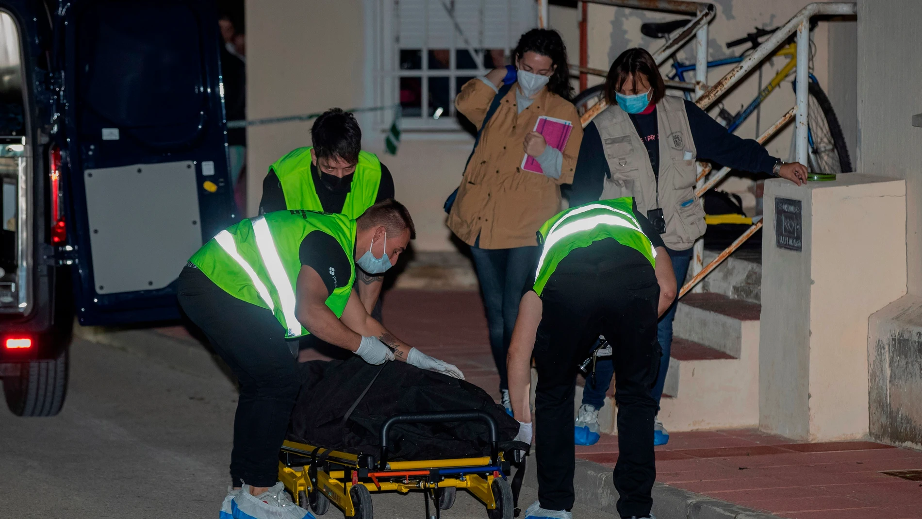 Varios trabajadores de una funeraria trasladan el cuerpo de un hombre de 53 años, apuñalado de muerte por su hijo este lunes en Campos del Río