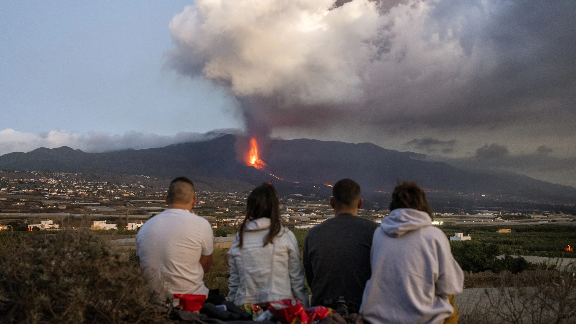 Cuatro residentes de La Palma contemplan el volcán que sigue en erupción tras 39 días. (AP Photo/Emilio Morenatti)
