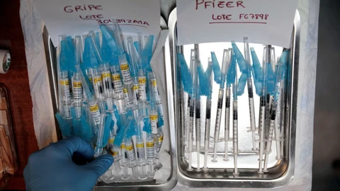 En la imagen, un sanitario prepara dosis de la vacuna contra la gripe y de refuerzo de la covid-19