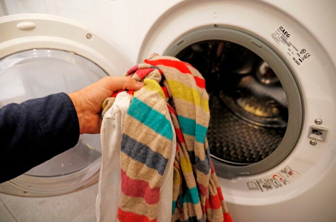 Una persona introduce ropa sucia en una lavadora