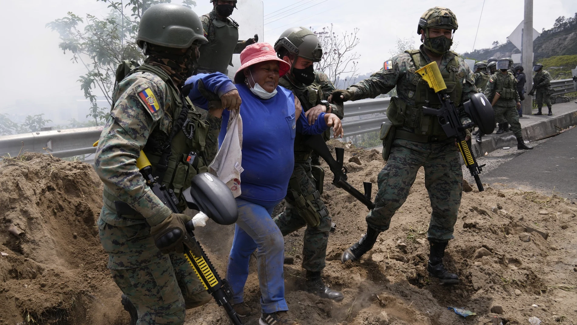 Soldiers come to the aid of a women affected by teargas during a protest against the rise in gas prices and the policies of Ecuador's President Guillermo Lasso, on the second day of a general, nation-wide strike, in Quito, Ecuador, Wednesday, Oct. 27, 2021. (AP Photo/Dolores Ochoa)