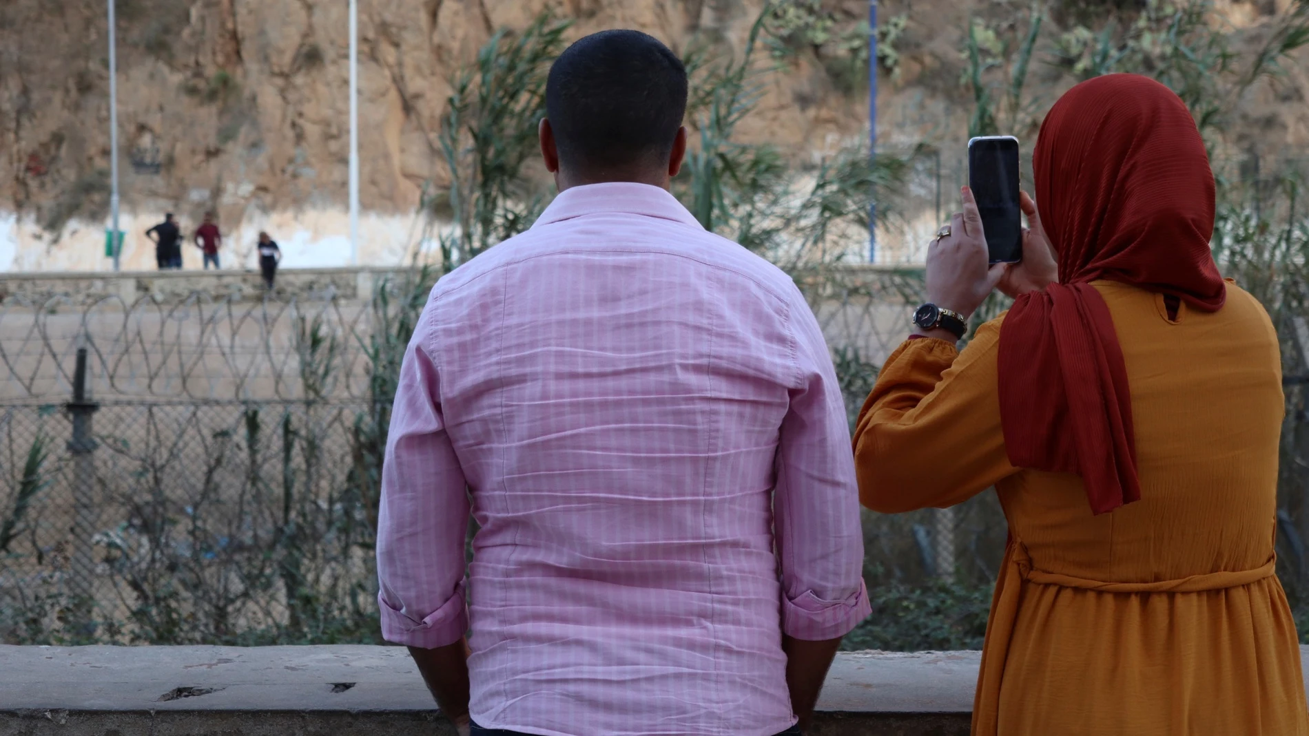 Familiares y personas curiosas saludan a los argelinos en la zona de Bin Lajraf. Una madre rompe a llorar al ver a su hija que le saluda moviendo la mano desde lejos, bajo la mirada de Hasan, vendedor ambulante de café y testigo de historias que se repiten cada día.