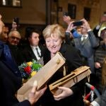 Outgoing German Chancellor Angela Merkel and France's President Emmanuel Macron receive flowers and a bottle of wine as gifts upon their arrival for talks, in Beaune, France, November 3, 2021. Philippe Desmazes/Pool via REUTERS