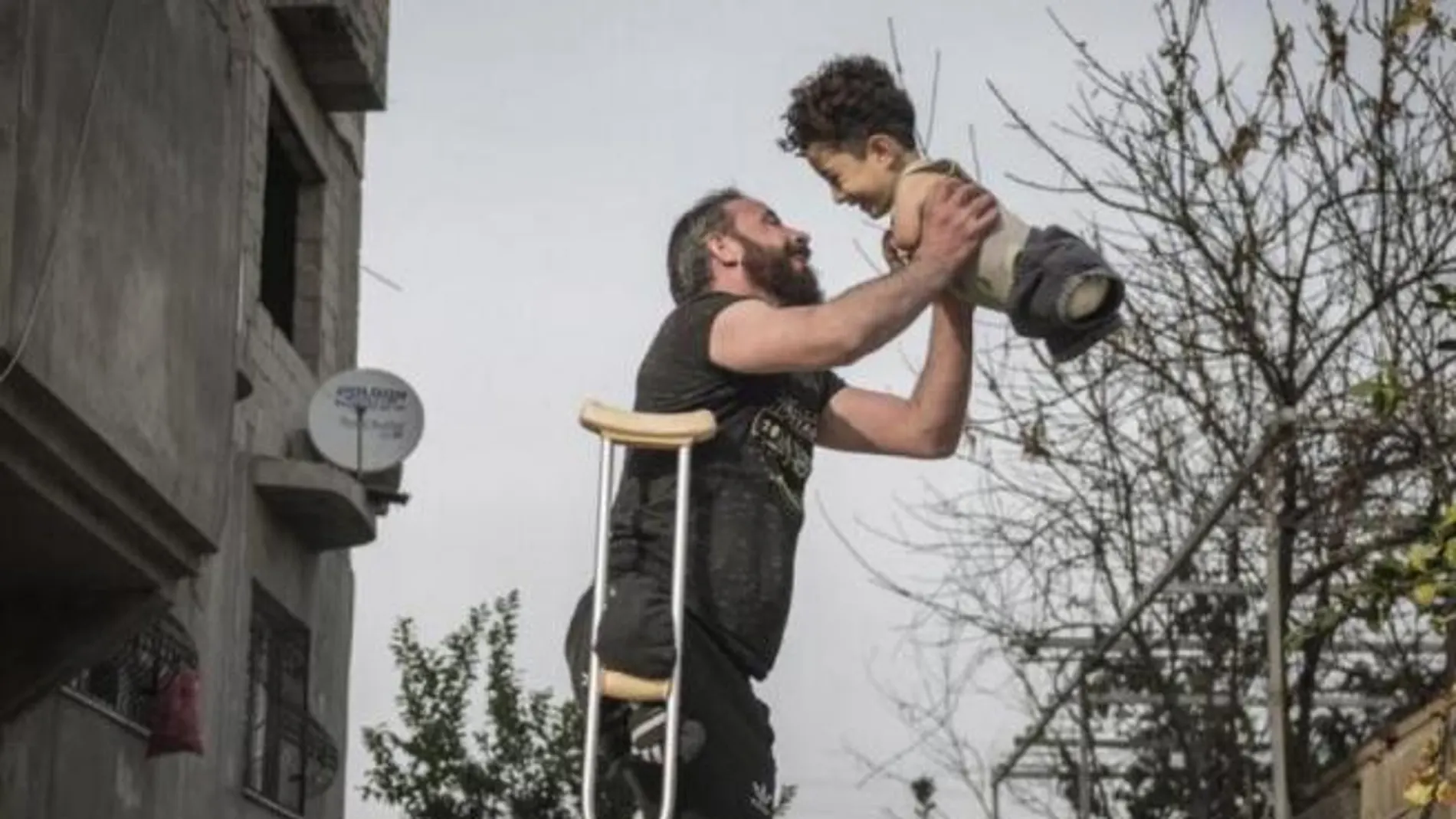 La imagen ganadora de los Siena International Photo Award en la que se ve a un niño refugiado sirio sin extremidades que sonríe mientras juega con su padre