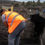 Varios voluntarios trabajan retirando cenizas de los tejados de casas próximas al volcán
