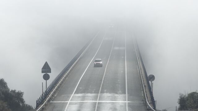 Un vehículo circula por Ponferrada ante una espesa niebla