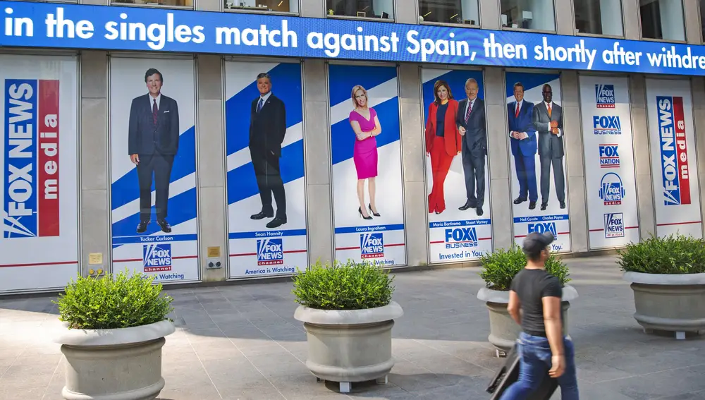 FILE - A man walks past promotional posters outside Fox News studios at News Corporation headquarters in New York on Saturday, July 31, 2021. From left to right are hosts Tucker Carlson, Sean Hannity, Laura Ingraham, Maria Bartiromo, Stuart Varney, Neil Cavuto and Charles Payne. A study by the Kaiser Family Foundation says that people who trust Fox News Channel and other outlets that appeal to conservatives are more likely to believe COVID-19 falsehoods than those who go elsewhere for news. (AP Photo/Ted Shaffrey, File)