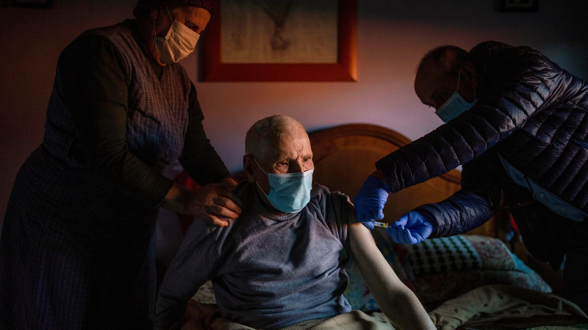 El enfermero José Ramón administra este jueves a un hombre la tercera dosis de la vacuna contra el coronavirus, en un domicilio de Avión, en Orense