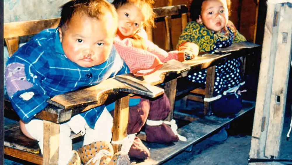 Fotograma del reportaje "Las habitaciones de la muerte" donde se observa a tres niñas chinas atadas a las sillas y desatendidas durante horas