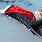 Un hombre retira hielo del parabrisas de su vehículo