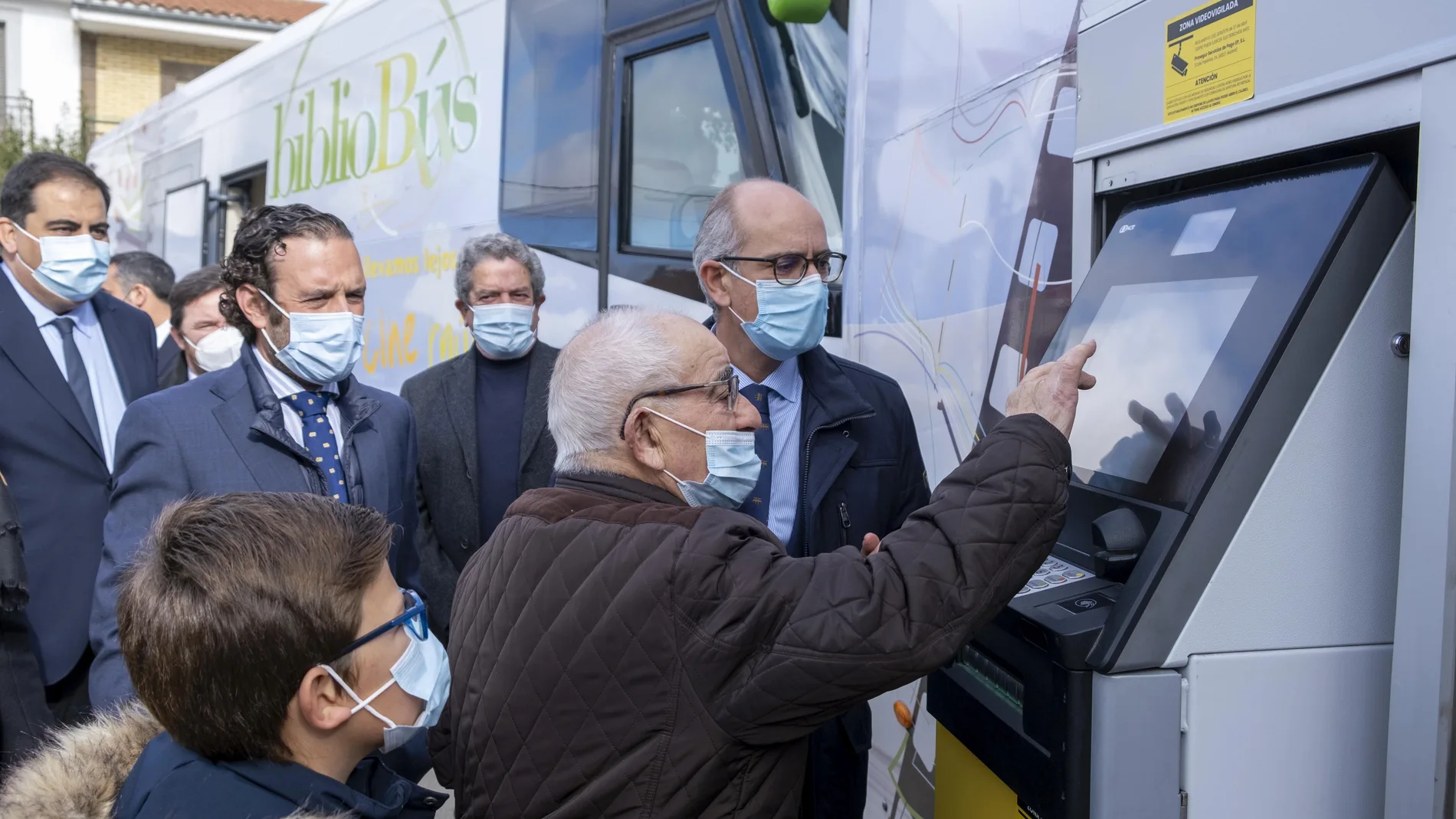 Manuel saca dinero junto a su bisnieto Óscar del cajero instalado en el bibliobús inaugurado hoy en Matilla de los Caños, en la imagen junto al presidente de la Diputación de Salamanca, Javier Iglesias