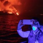 Un turista en barco fotografía la erupción volcánica desde el puerto de Tazacorte