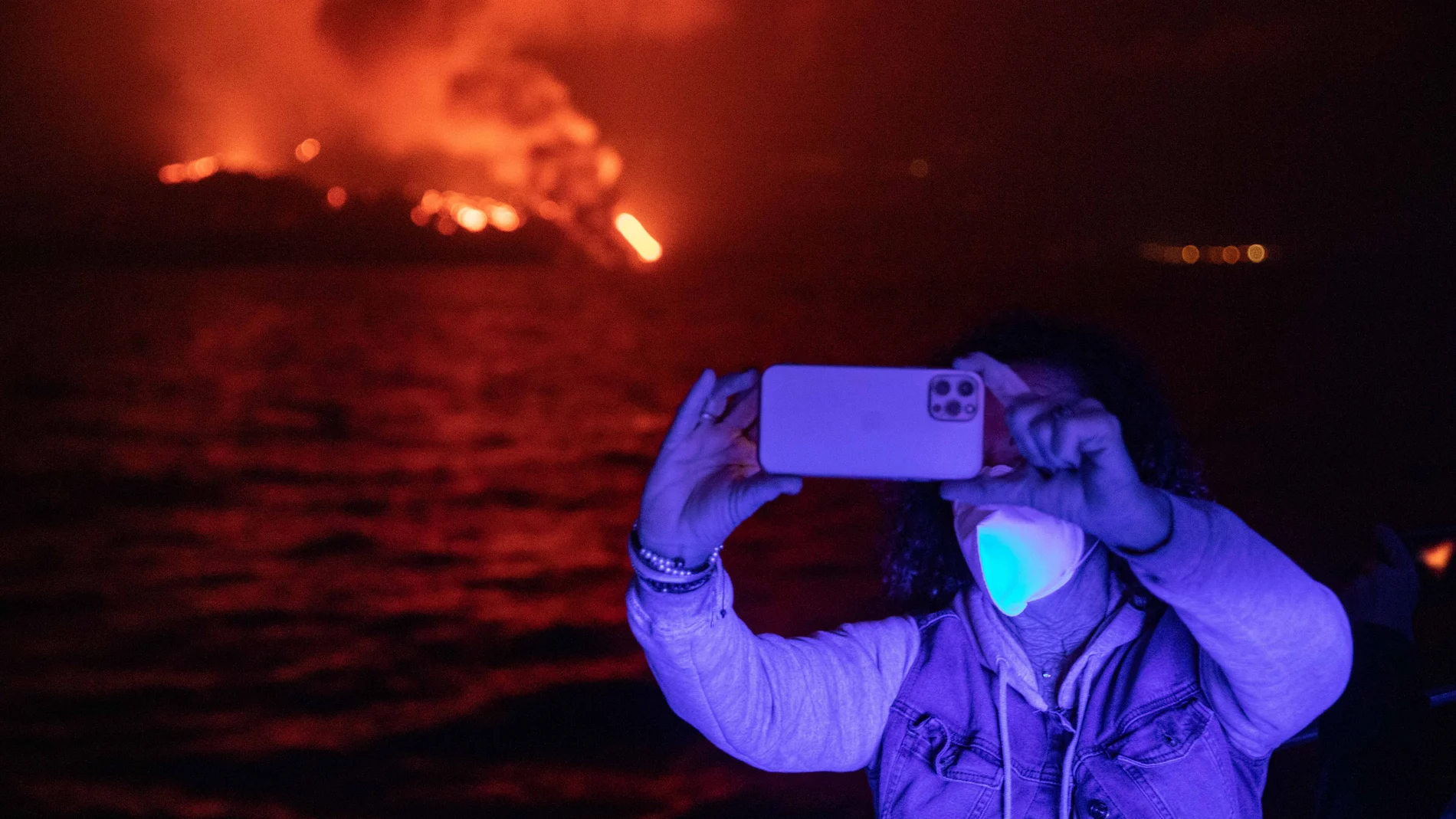 Un turista en barco fotografía la erupción volcánica desde el puerto de Tazacorte