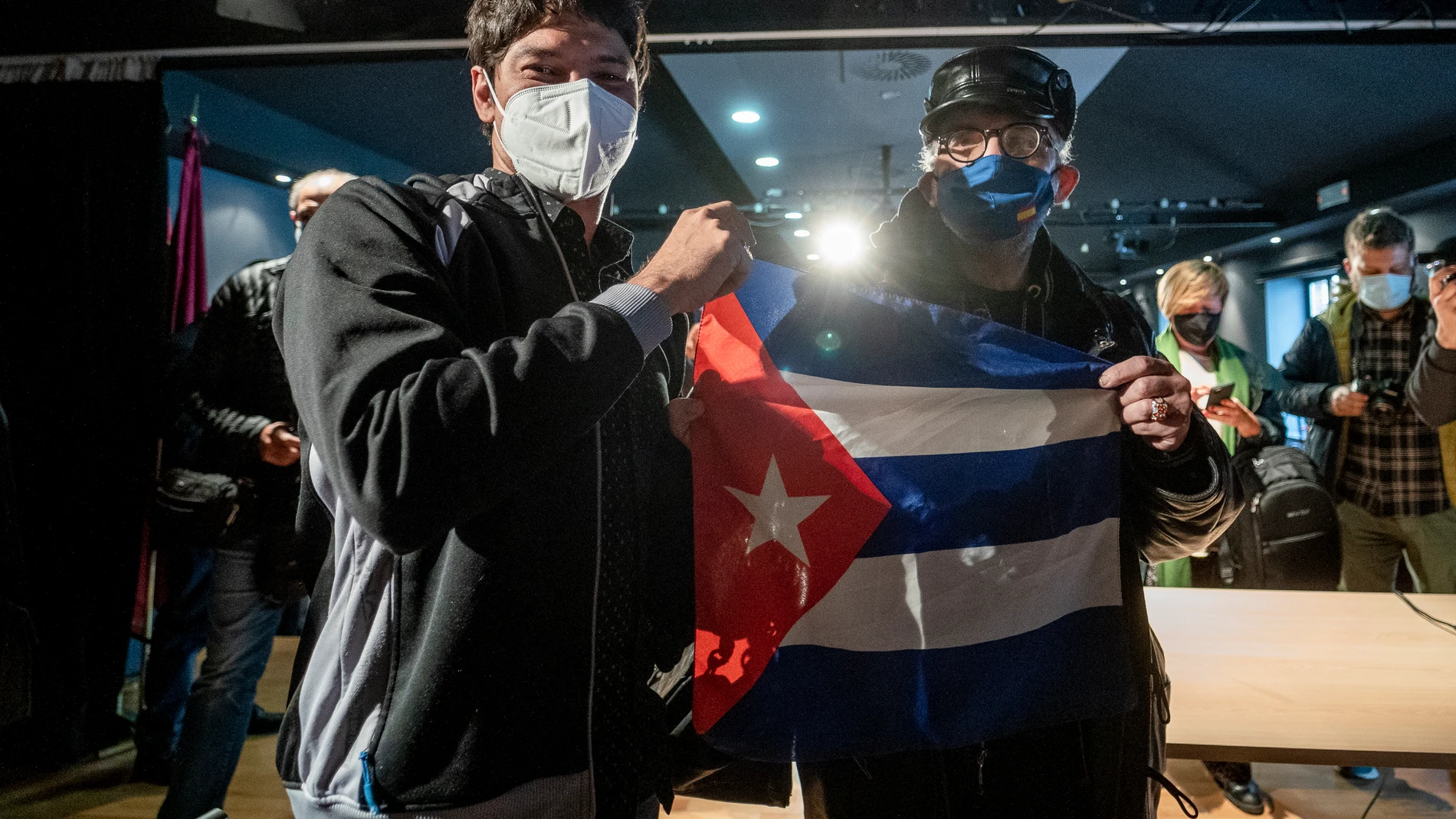 Yunior García Aguilera, impulsor del #15NCuba (i), posa con un hombre con una bandera de Cuba después de comparecer en rueda de prensa, en el Centro Cultural Galileo