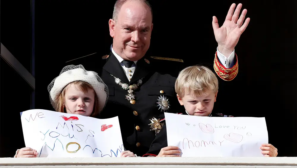 El Príncipe Alberto II de Mónaco saluda mientras sus hijos, el Príncipe Jacques (d) y la Princesa Gabriella (i), sostienen mensajes. EFE / SEBASTIEN NOGIER