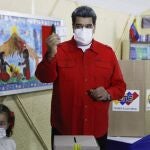 Nicolas Maduro acompañado de su nieta enseña la papeleta antes de depositarla en la urna de cartón