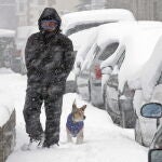 Un hombre camina junto a su perro por una calles cubierta de nieve