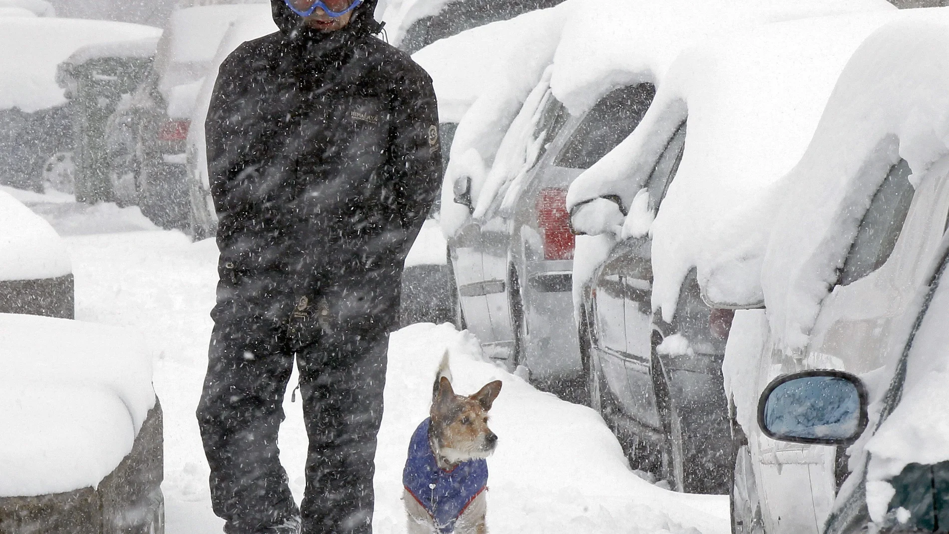 Un hombre camina junto a su perro por una calles cubierta de nieve