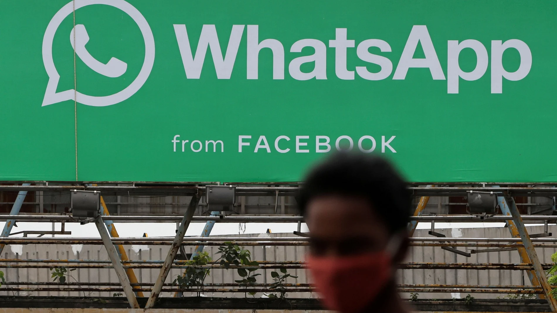 Un hombre junto a una publicidad de Whatsapp en India