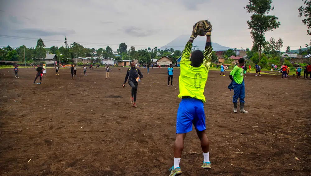 Jóvenes entranan al fútbol en Ngangi Don Bosco con el volcán Nyiragongo al fondo en Goma (Congo)