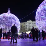 Un grupo de personas asiste al acto de encendido de la iluminación navideña de la plaza del Ayuntamiento en Valencia