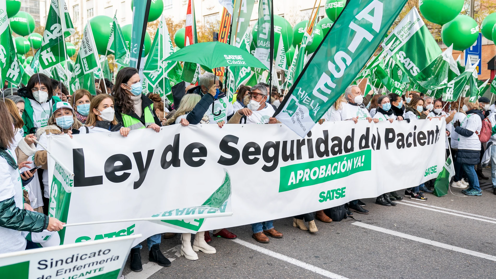 Un grupo de personas con una pancarta en la que se lee: `Ley de seguridad del paciente, aprobación ya!´, participa en una concentración de enfermeros, en la Plaza de las Cortes frente al Congreso de los Diputados