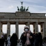 Una mujer posa con mascarilla ante la Puerta de Brandenburgo, en Berlín