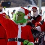 Un Grinch entre mucho Santa Claus se toma un selfie en Estados Unidos.