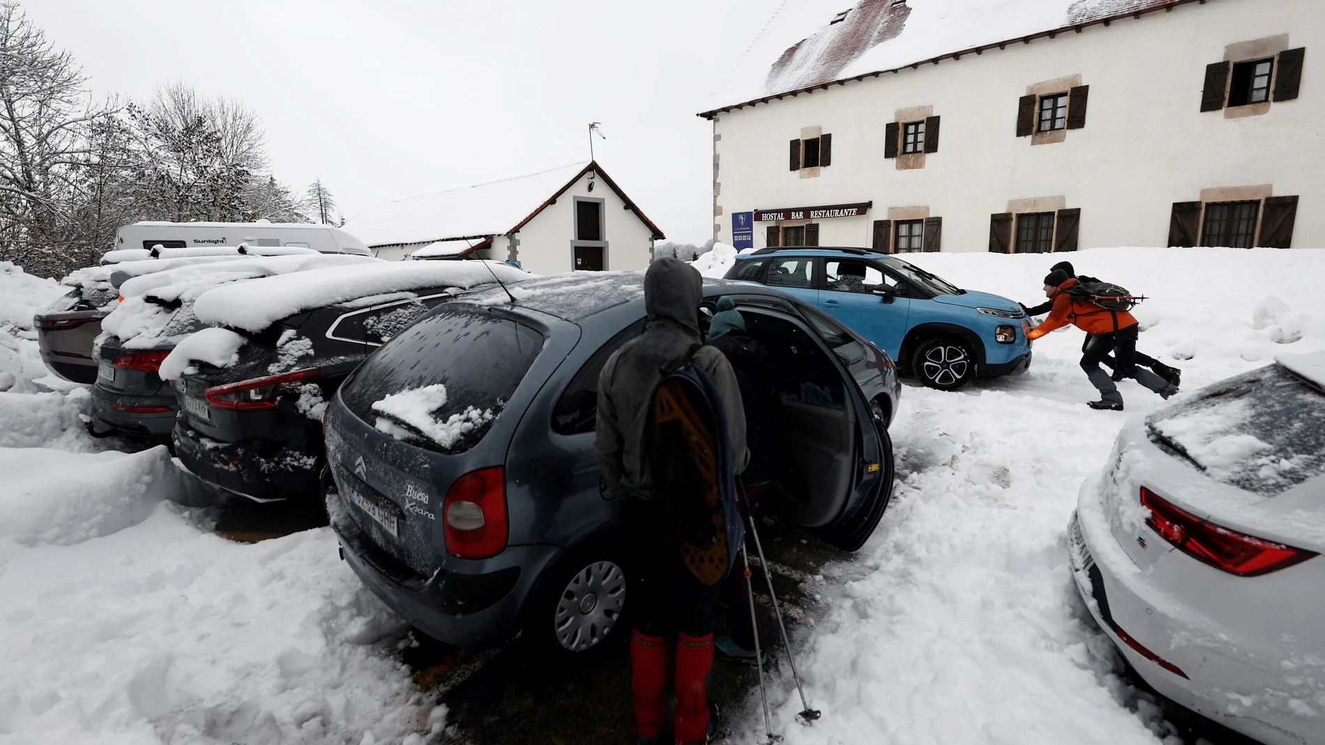 Dos personas empujan un vehículo atrapado en el parking de Roncesvalles tras las intensas nevadas que se han registrado estos días