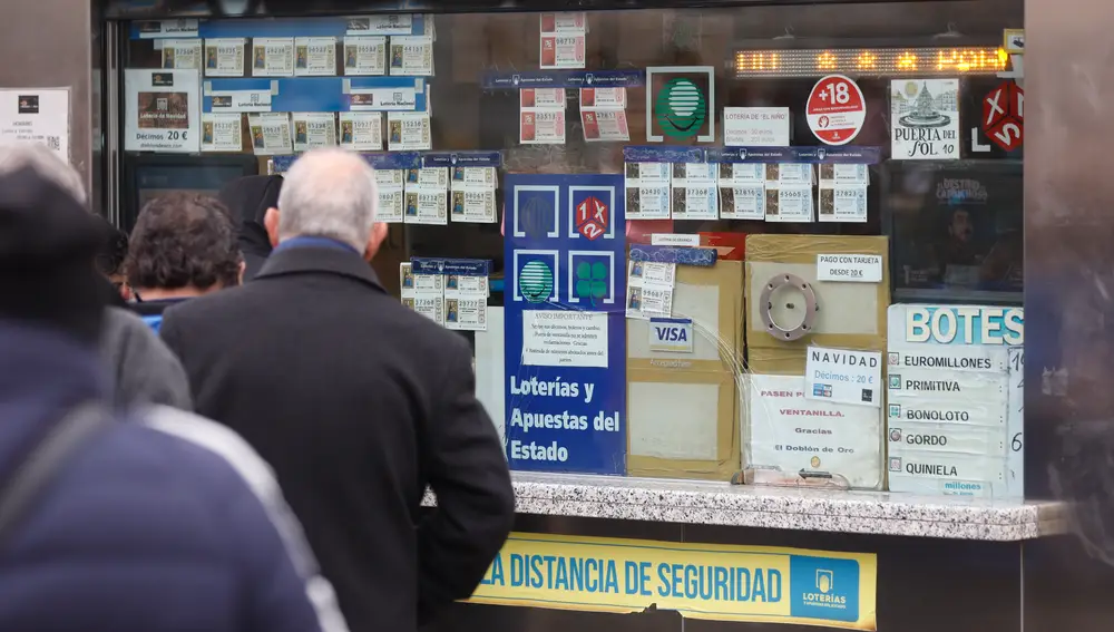 Varias personas en una administración de lotería de Navidad de la Puerta del Sol cuando queda una semana para el Sorteo Extraordinario de la Lotería de Navidad