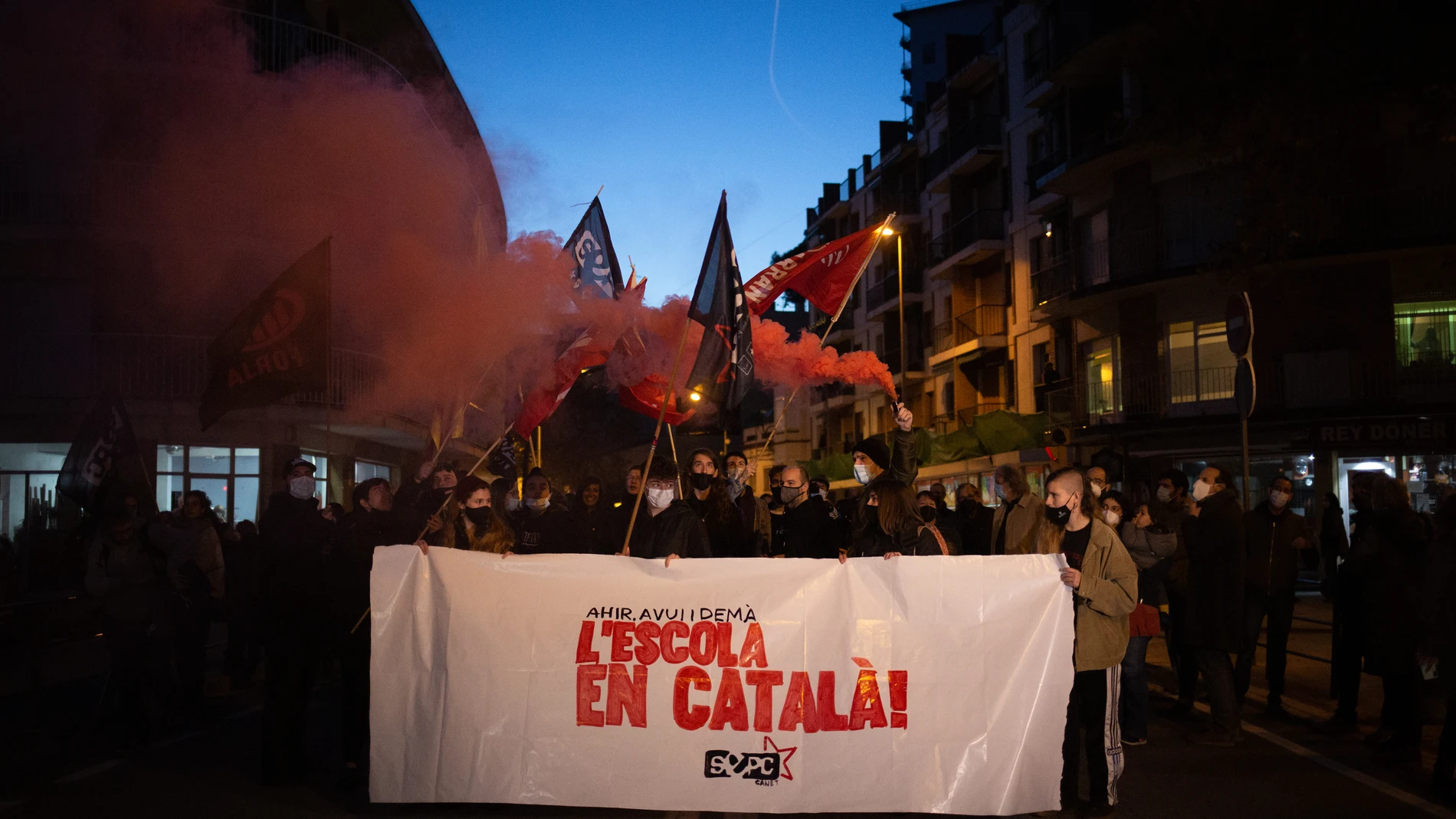 Varias personas con una pancarta en la que se lee: 'L'escola en català', durante una manifestación en Canet de Mar