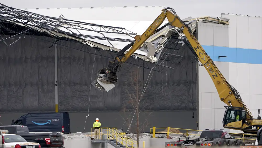 Workers use equipment to remove a section of roof left on a heavily damaged Amazon fulfillment center Saturday, Dec. 11, 2021, in Edwardsville, Ill. The a large section of the roof of the building was ripped off and walls collapsed when a strong storms moved through area Friday night. (AP Photo/Jeff Roberson)