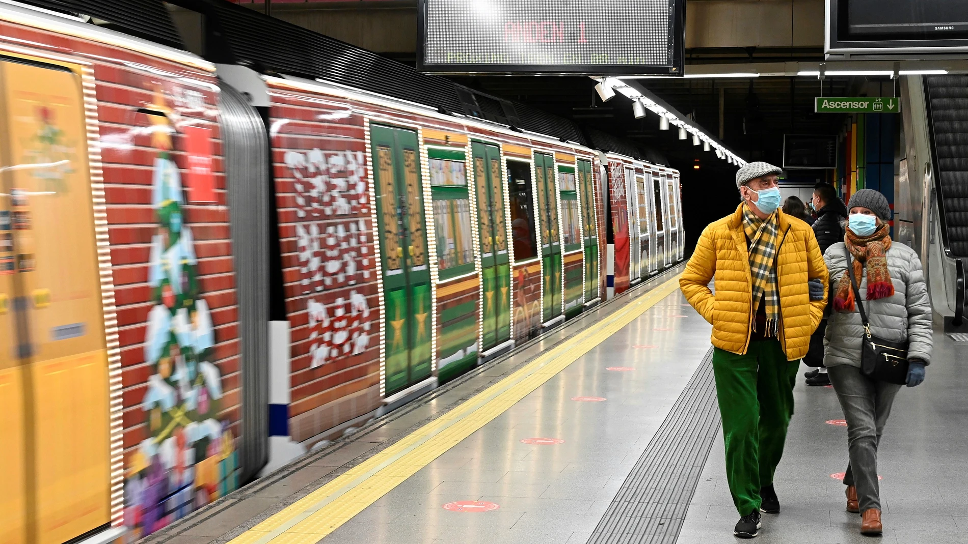 MADRID, 13/12/2021.- Varias personas caminan junto al tren de la línea 6 de metro de Madrid decorado con motivos navideños. EFE/ Fernando Villar