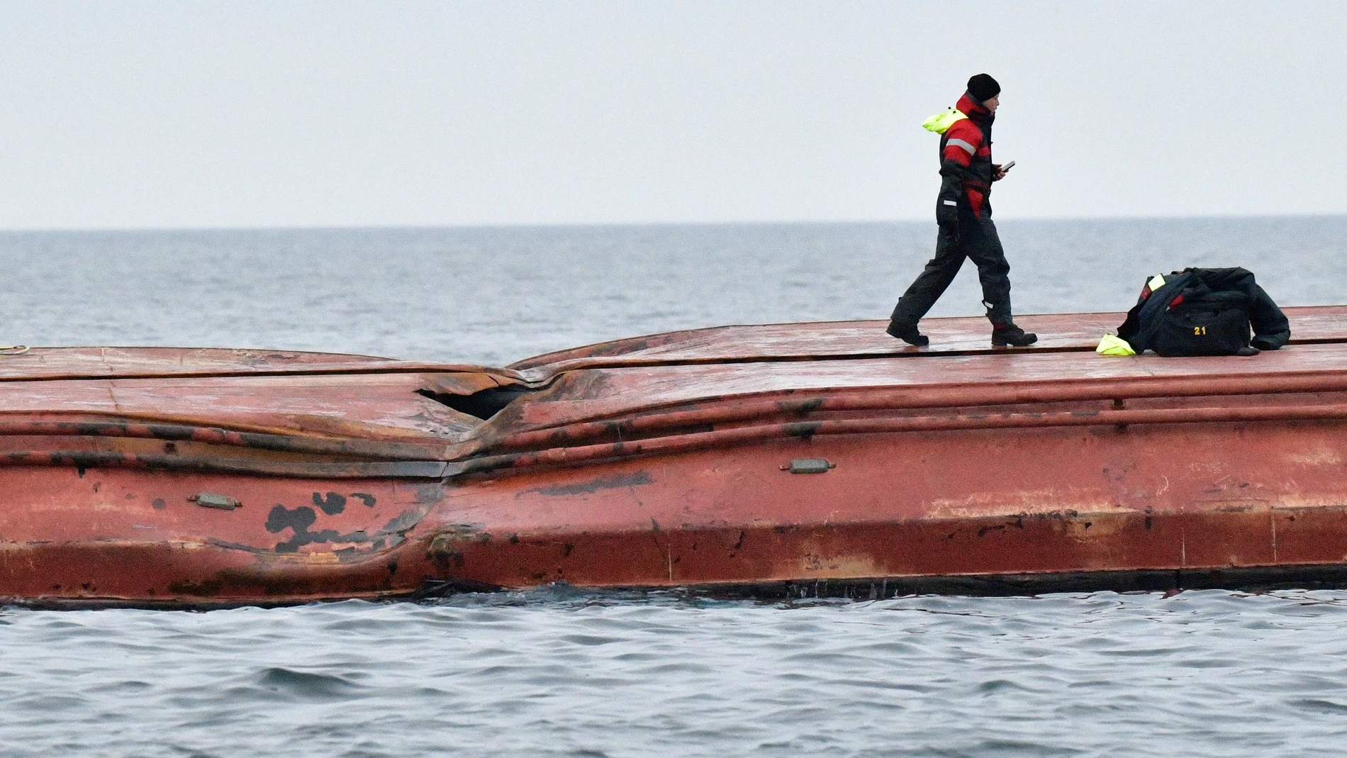 Un miembro de salvamento marítimo camina sobre el casco del carguero danés Karin Hoej volcado tras colisionar con el carguero británico Scot Carrier en el Mar Báltico