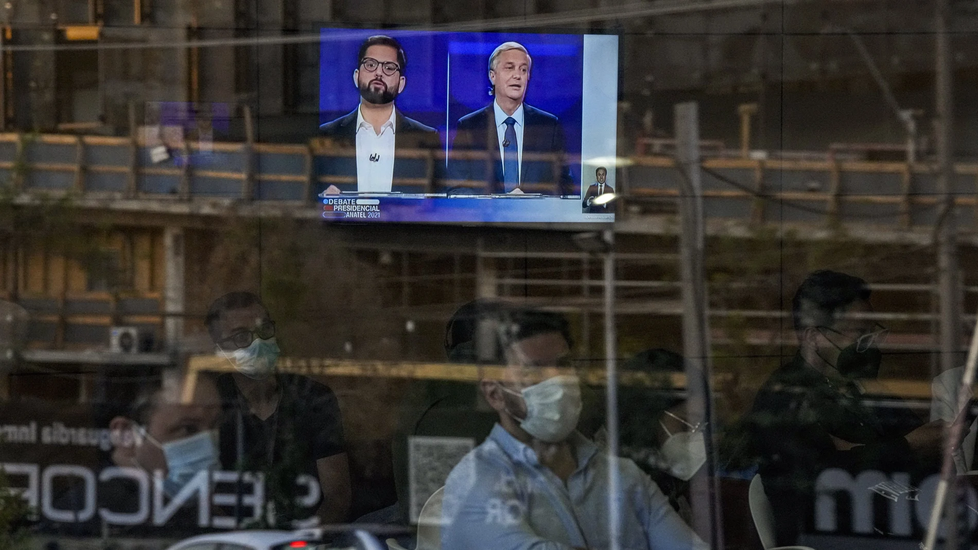 Journalists watch the debate between presidential candidate Gabriel Boric from the Apruebo Dignidad coalition party, and presidential candidate Jose Antonio Kast from the Partido Republicano in a hall of the National Television Channel in Santiago, Chile, Monday, Dec. 13, 2021. Chile votes in the runoff election on Dec. 19. (AP Photo/Esteban Felix)