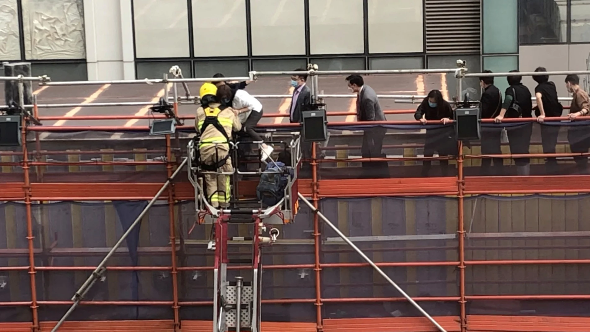 Firefighters use a crane to rescue people lined up on a roof after a fire broke out at the World Trade Centre in Hong Kong, China, December 15, 2021 in this still image obtained from a social media video. Wing Shun Kwok/via REUTERS THIS IMAGE HAS BEEN SUPPLIED BY A THIRD PARTY. MANDATORY CREDIT.
