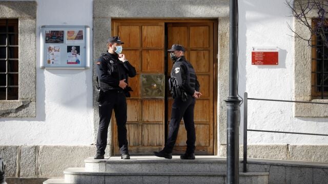 Miembros de la Policía Local d San Martín de Valdeiglesias vigilan el acceso al consistorio mientras integrantes del grupo de intervención de delitos financieros de la Guardia Civil registran la sede del Ayuntamiento