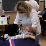 Un padre abraza a su hijo mientras es vacunado por el personal sanitario cuando este miércoles la Generalitat
