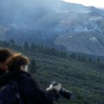 Dos turistas en el mirador de Tajuya toman fotografías del volcán Cumbre Vieja sin actividad en las últimas horas, en la isla canaria de La Palma
