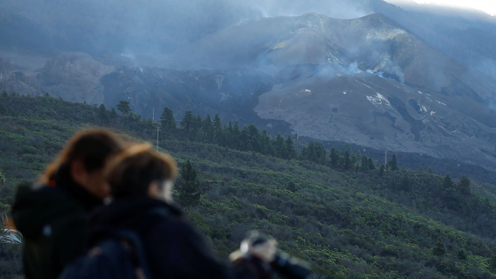 Dos turistas en el mirador de Tajuya toman fotografías del volcán Cumbre Vieja sin actividad en las últimas horas, en la isla canaria de La Palma