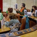 La líder de Adelante Andalucía, Teresa Rodríguez (i), junto al resto de diputados no adscritos muestran fotografías de personas desaparecidas momentos antes de abandonar el salón de plenos. EFE/Julio Muñoz