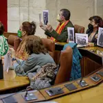 La líder de Adelante Andalucía, Teresa Rodríguez (i), junto al resto de diputados no adscritos muestran fotografías de personas desaparecidas momentos antes de abandonar el salón de plenos. EFE/Julio Muñoz