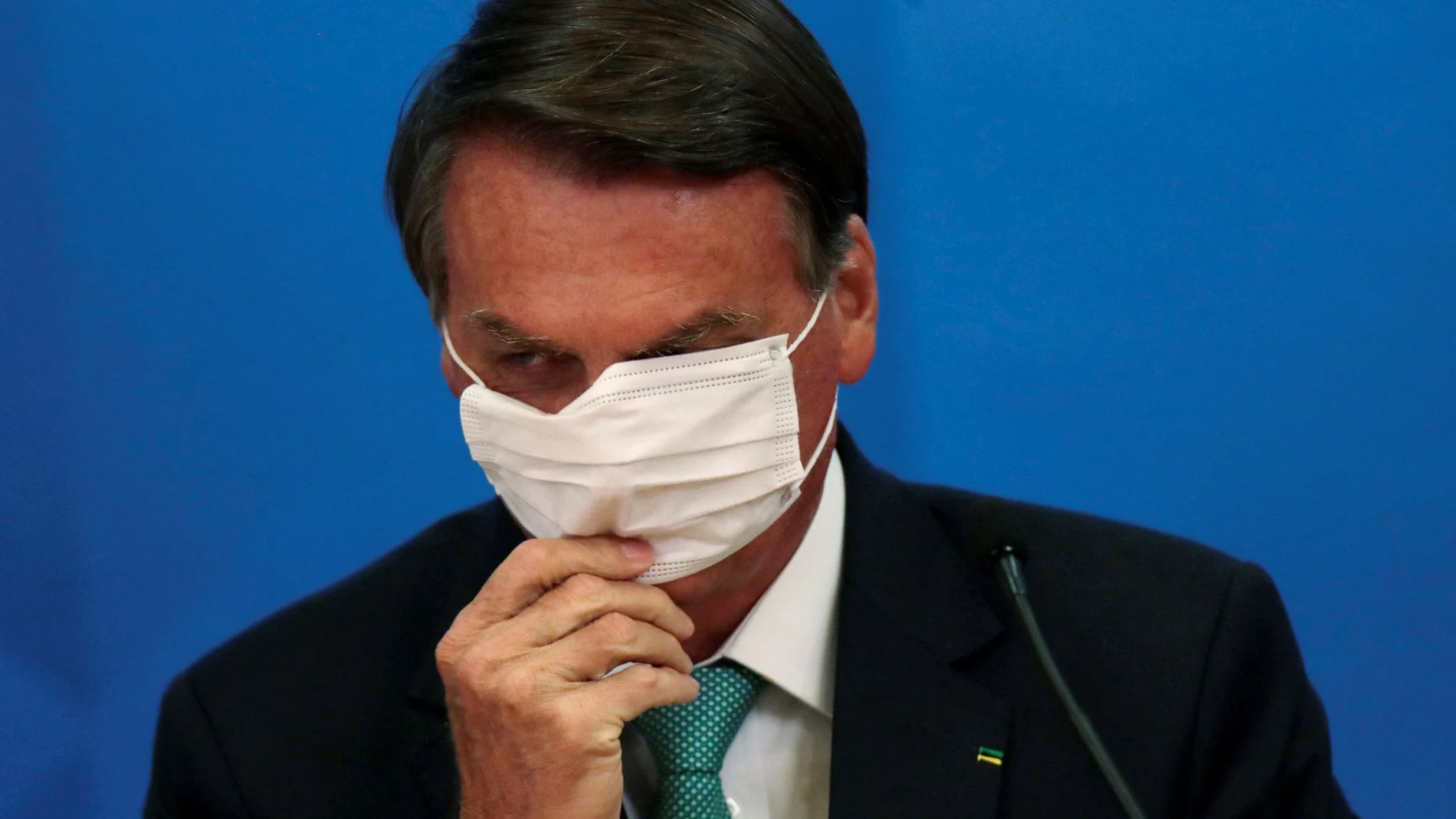 FILE PHOTO: Brazil's President Jair Bolsonaro adjusts his protective face mask during a ceremony of signing the Vaccine Technology Transfer Agreement for Oxford/AstraZeneca coronavirus disease (COVID-19) vaccines, in Brasilia, Brazil, June 1, 2021. REUTERS/Ueslei Marcelino/File Photo